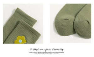 Macro detail of olive green ribbed cotton socks with yellow floral embroidery