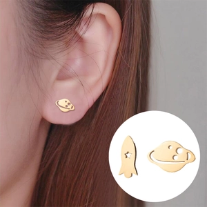 Minimalist golden stainless steel spaceship and Saturn stud earrings on model's ear