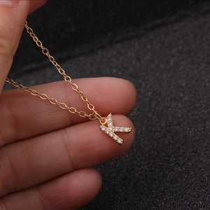 Minimalist gold necklace with a zircon-inlaid letter K pendant on a fine link chain