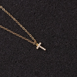 Detailed view of a gold chain necklace with a zircon-encrusted letter T pendant on black foam