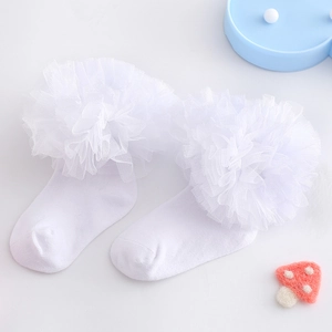 Detail von weißen Baumwoll-Babysocken mit weichem Spitzenrand auf einem weißen Tisch