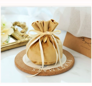 Detail of ginger velvet drawstring gift bag with gold heart pendant and ribbon bow