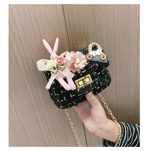 Dettaglio mini borsa in tweed con tracolla a catena dorata e ciondoli a forma di bambola