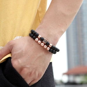 Close-up of matte black beads and rose gold crown bracelet set worn on wrist