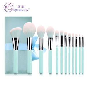 Detail of 13-piece mint green makeup brush set with pink gradient bristles and bow case