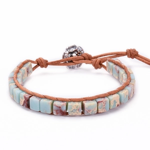Gros plan des perles de pierre carrées et du fermoir fleur en argent sur bracelet cuir