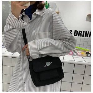 Detailed view of black canvas crossbody bag with planet embroidery and adjustable strap