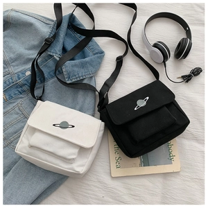 Detail of canvas crossbody bag with planet embroidery and adjustable strap in casual setting