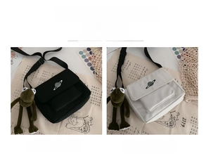 Detail of canvas messenger bags in black and white with planet print and frog mascot