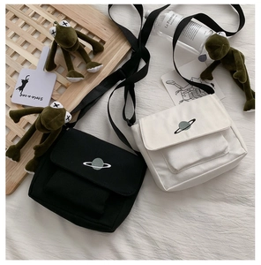 Close-up of embroidered planet on black and off-white canvas crossbody bags