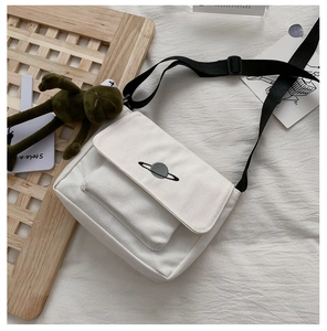 Detail of canvas messenger bag with planet embroidery on white wrinkled bedsheet