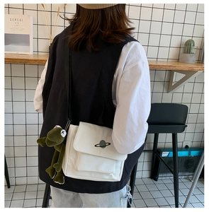 Detailed close-up of white canvas satchel featuring planet embroidery and a frog mascot