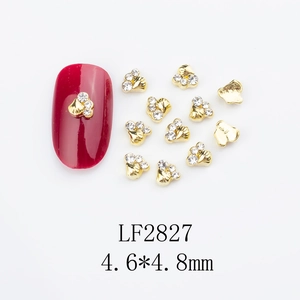 Macro detail of gold alloy heart nail charms with three white rhinestones and size data