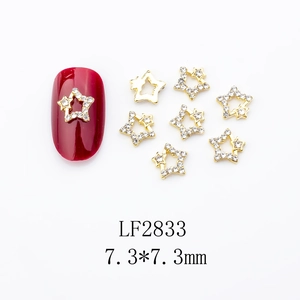 Close-up of gold star nail charms with white crystals on a red manicured nail