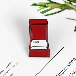 Detail shot of a red jewelry box brooch featuring a white creative Esc keyboard key design