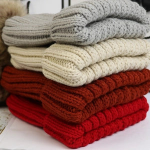 Details von dicken Strickmützen in Grau, Beige, Karamell und Rot mit Kunstpelz-Bommel