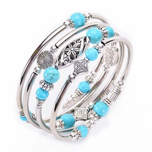 Detail of silver layered bracelet with turquoise beads and bohemian charms on white background