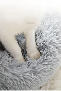 Close-up of soft plush texture on grey pet bed showing a cat kneading the long fur fabric