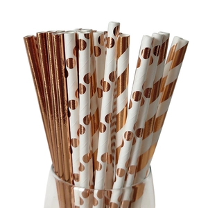 Rose gold paper straws set with solid, polka dot and striped patterns in a glass cup