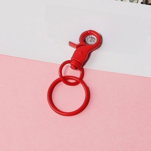 Detail showing high-gloss red metal lobster clasp and key rings on minimalist background