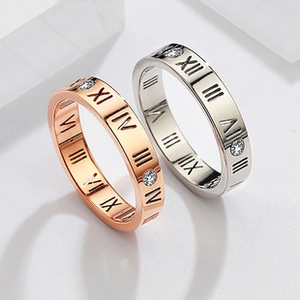 Detail of rose gold and silver titanium rings featuring Roman numerals and small gemstones