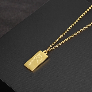 Macro shot of 18K gold rectangle pendant with Love cursive engraving on O-chain necklace
