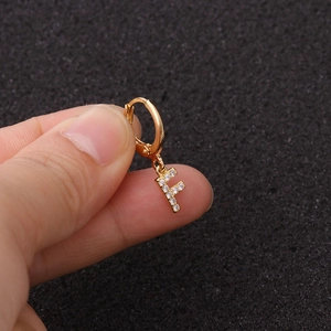 Détail de la boucle d'oreille dorée lettre F avec des pierres en zircone cubique