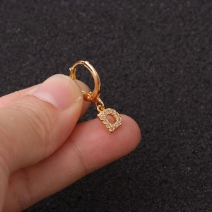 Vue macro d'une boucle d'oreille créole lettre D dorée sertie de zircons