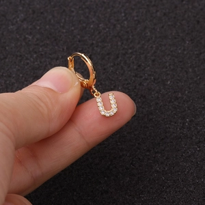 Gros plan sur une boucle d'oreille en or avec pendentif lettre U serti de zircons brillants