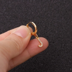 Détail du bijou d'oreille doré avec pendentif lettre J et zircons scintillants
