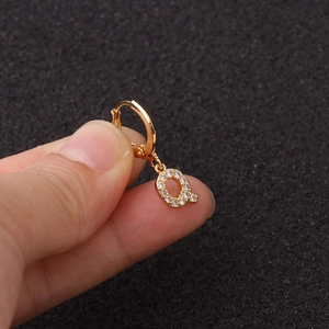 Gros plan détaillé d'une créole dorée avec pendentif lettre Q serti de zircons