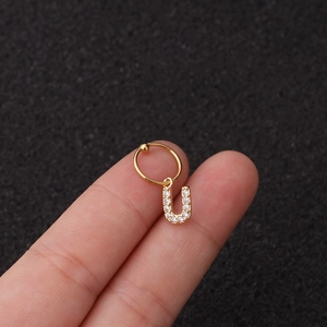 Gros plan d'une boucle d'oreille dorée lettre U avec cristaux étincelants