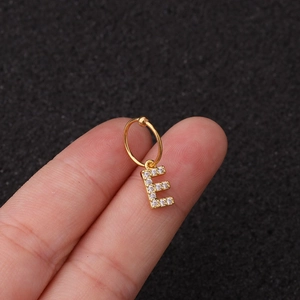 Gros plan d'une boucle d'oreille en or avec pendentif lettre E serti de zircons brillants