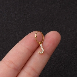 Vue macro d'un anneau de piercing doré avec pendentif lettre J en zircon sur le bout du doigt