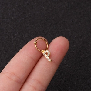 Gros plan sur une boucle d'oreille créole dorée avec un pendentif lettre P en zircon