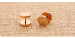 Macro detail of rose gold round disc stud earrings on woven texture background