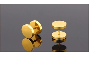 Macro shot of gold-plated titanium steel barbell stud earrings with a mirrored reflection