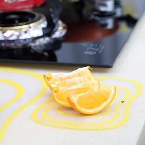 Flexible frosted transparent kitchen cutting board with yellow wavy border and orange slices