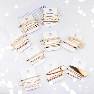 Close-up of golden pearl hair clip set with geometric and minimalist designs on cards