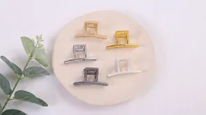 Minimalistisches Set aus Metall-Haarklammern in fünf Farben auf einem neutralen Display