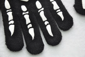 Detail showing the knitted texture and bone pattern on kids' glow skull gloves