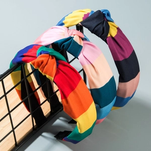 Close-up of wide knotted headbands featuring vibrant multi-colored striped fabric textures