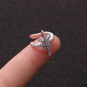 Close-up of star shaped silver ear cuff with zircon rhinestones on a textured background