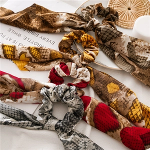 Flat lay detail of leopard and snake print scrunchies with streamers on a neutral cloth