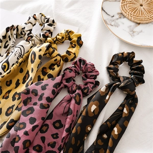 Flat lay of leopard print hair scrunchies with long ribbons on a marble tray