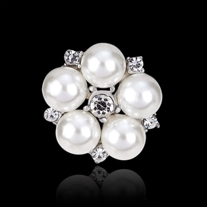 Macro shot of clear rhinestone flower brooch with inlaid white pearls on silver base