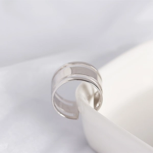 Close-up of three-layered polished S925 silver ring on a white ceramic plate edge
