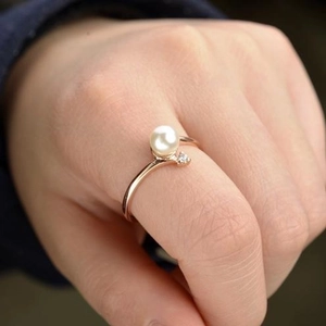 Elegant rose gold pearl ring with small zircon accent worn on a woman's finger