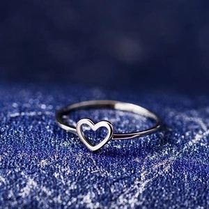 Elegant minimalist silver hollow heart ring made of silver-plated copper on blue textured background
