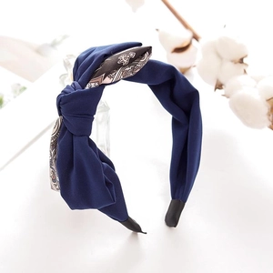 Navy blue fabric headband with contrast pattern bow tie on a clean white surface